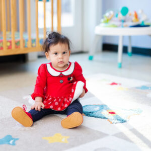 Early Head Start Toddler sits on colorful rug.